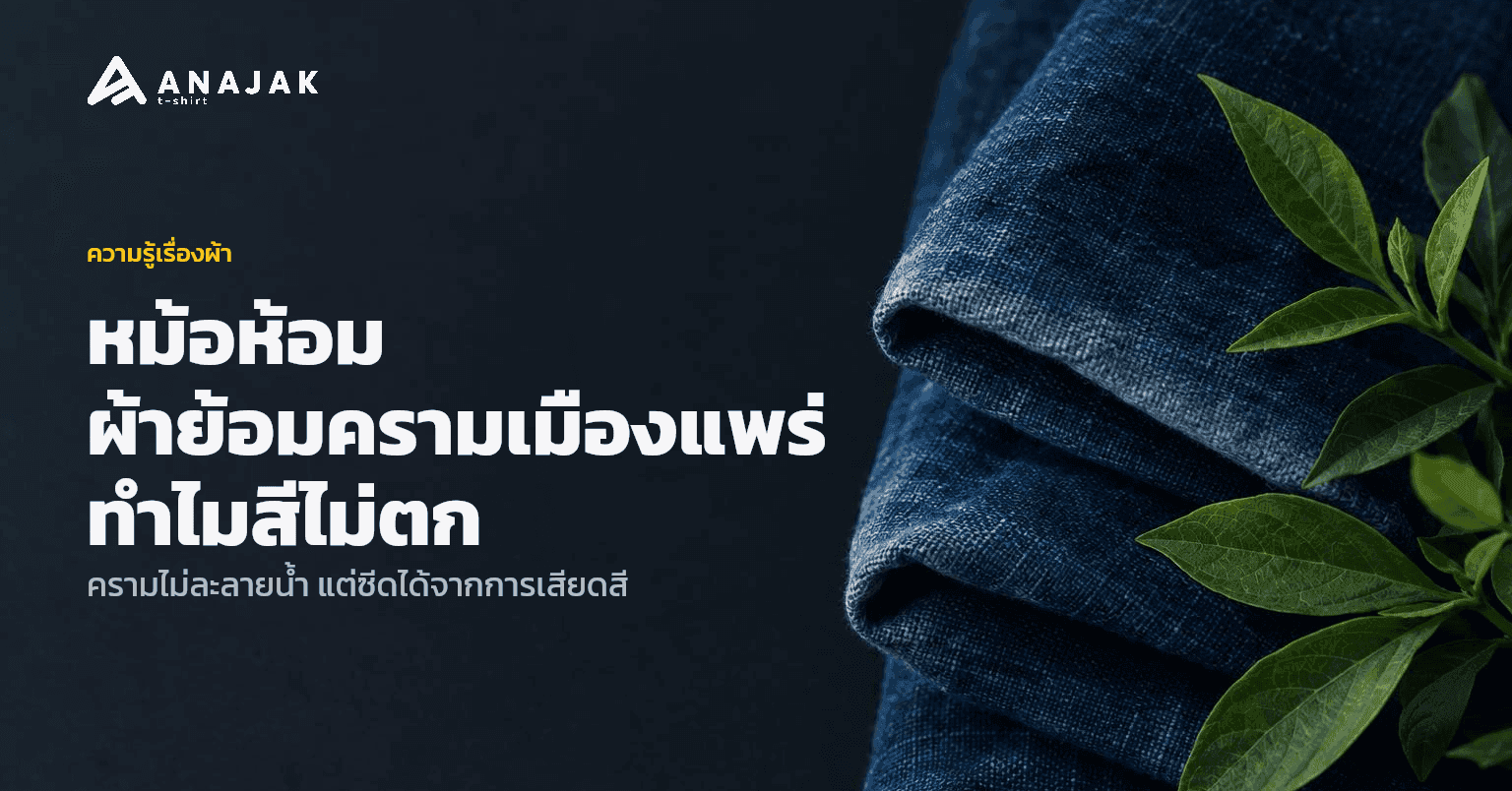 ผ้าฝ้ายย้อมครามสีน้ำเงินเข้มพับวางคู่ใบห้อมสด ขอบผ้าบางจุดซีดเป็นฟ้าอ่อนตามธรรมชาติของผ้าย้อมคราม
