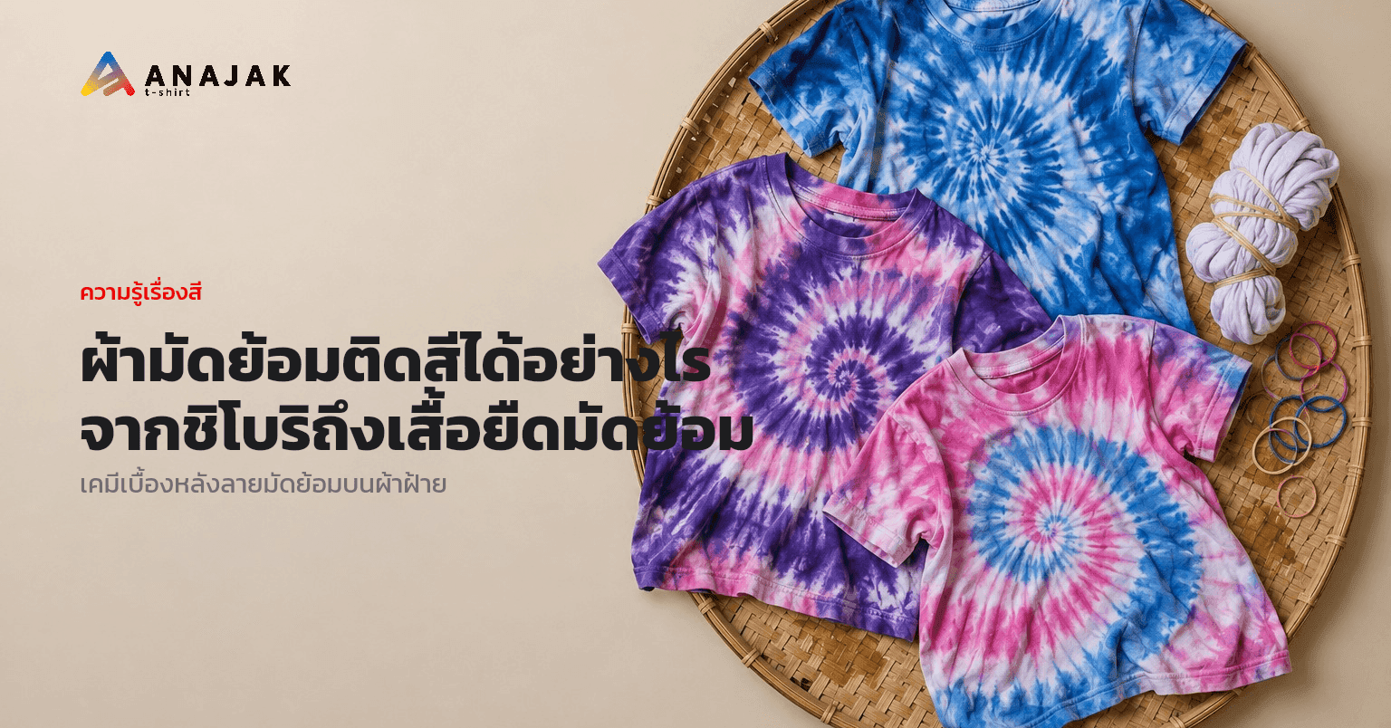 เสื้อยืดคอตตอนมัดย้อมลายก้นหอยสีน้ำเงิน ม่วง และชมพู วางบนเสื่อไม้ไผ่ ข้างๆ มีหนังยางและเสื้อที่ยังมัดเชือกไว้