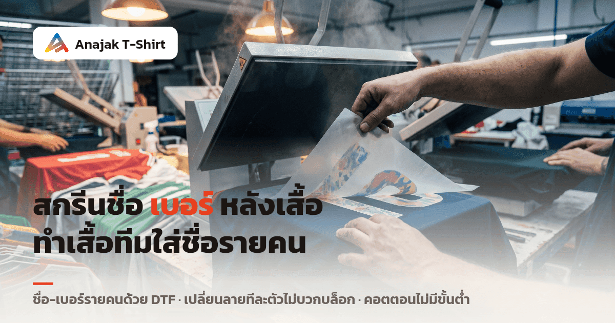 มือกำลังลอกฟิล์มทรานสเฟอร์ DTF ออกจากหลังเสื้อกีฬาสีกรมท่าบนเครื่องรีดร้อนในโรงงาน สื่อถึงงานสกรีนชื่อและเบอร์รายคนหลังเสื้อทีม