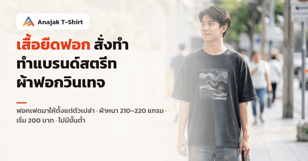ชายไทยใส่เสื้อยืดคอตตอนทรงโอเวอร์ไซส์สีดำฟอกเฟดโทนวินเทจ ยืนริมทางเท้าในเมือง เห็นเนื้อผ้าหนาอยู่ทรงและสีจางไม่เท่ากันทั้งตัว